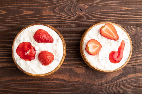 Grained cottage cheese with strawberry jam on brown wooden background. top view, flat lay, copy space