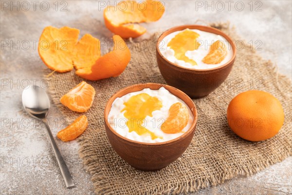 Grained cottage cheese with tangerine jam on brown concrete background and linen textile. side view, close up