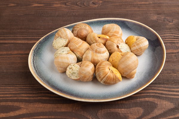 Grape (Burgundy) snails with butter and cheese on brown wooden background. Side view