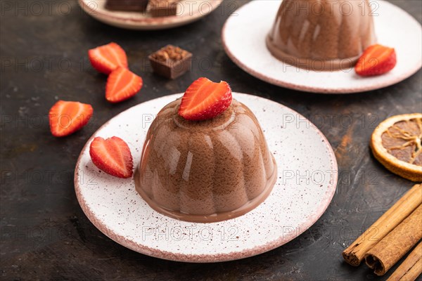 Chocolate jelly with strawberry on black concrete background. side view, close up