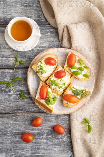 White bread sandwiches with cream cheese, tomatoes and microgreen on gray wooden background and linen textile. top view, flat lay, close up