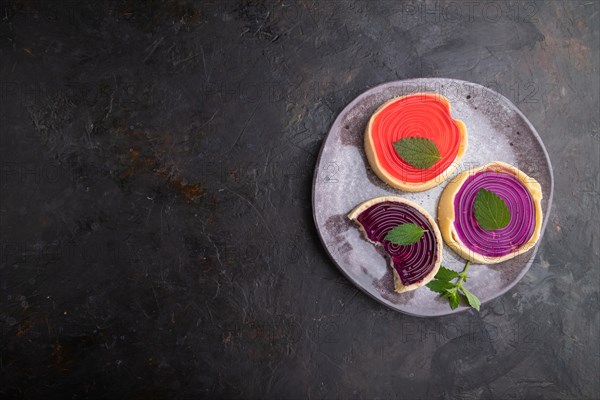 Sweet tartlets with jelly and milk cream on a black concrete background. top view, flat lay, copy space