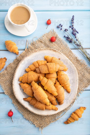 Homemade bagel roll with cup of coffee on a blue wooden background and linen textile. top view, flat lay, close up