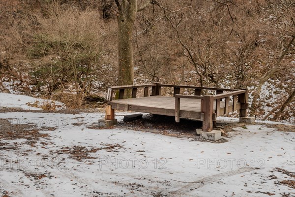 Old dilapidated wooden Korean picnic table in wilderness park on winter day in South Korea
