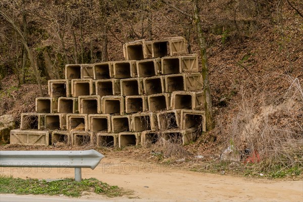 Square concrete culverts stacked in rows beside dirt road