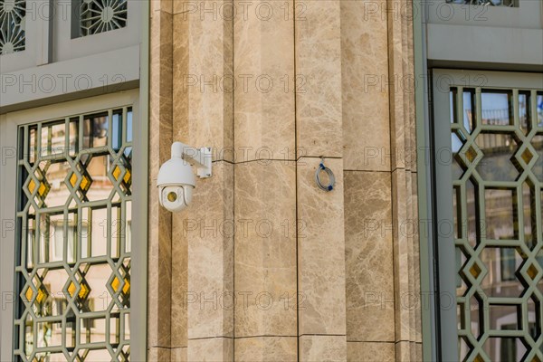 Closed circuit TV camera beside window frame of marble walled building in Istanbul, Tuerkiye