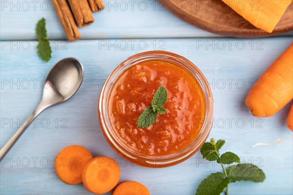 Carrot jam with cinnamon in glass jar on blue wooden background. Top view, flat lay, close up