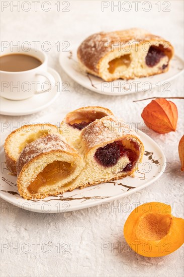 Homemade sweet bun with apricot jam and cup of coffee on gray concrete background. side view, close up