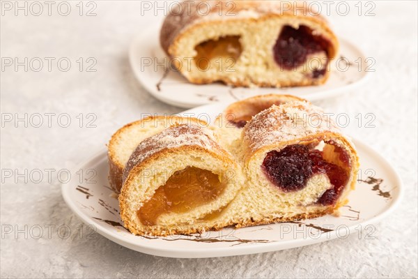 Homemade sweet bun with apricot jam on gray concrete background. side view, close up