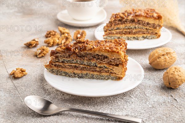 Walnut and hazelnut cake with caramel cream, cup of coffee on brown concrete background. side view