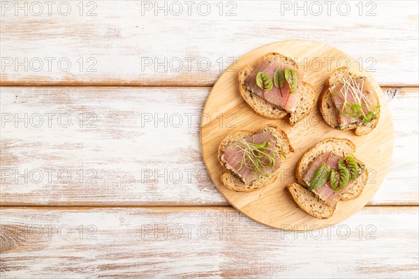 Bread sandwiches with jerky salted meat, sorrel and cilantro microgreen on white wooden background. top view, flat lay, copy space