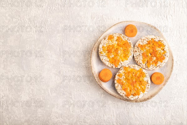 Carrot jam with puffed rice cakes on gray concrete background. Top view, flat lay, copy space