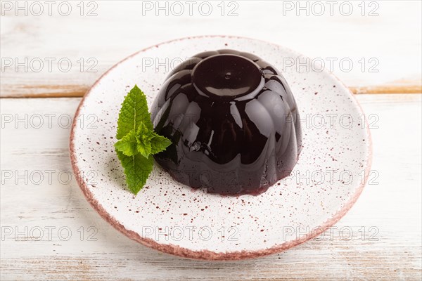 Black currant and grapes jelly on white wooden background. side view, close up