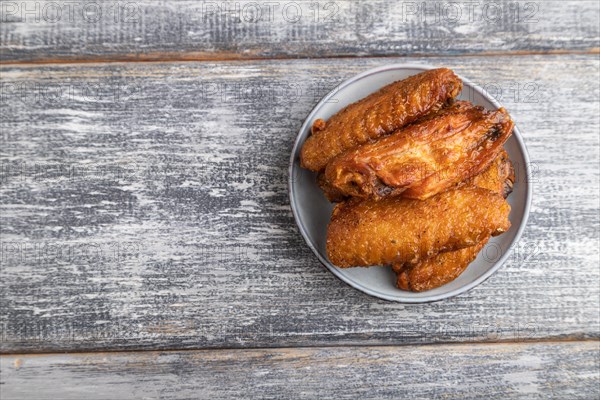 Fried chicken wings on a wooden plate on a gray wooden background. Top view, flat lay, close up, copy space