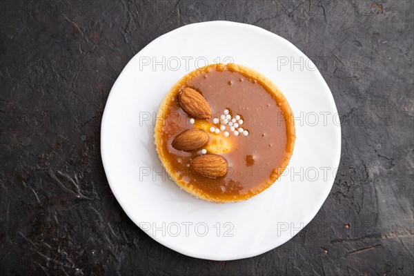 Sweet tartlets with almonds and caramel cream on a black concrete background. top view, flat lay, close up