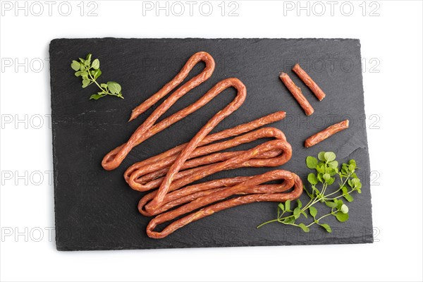 Traditional polish smoked pork sausage kabanos on a slate cutting board isolated on white background. Top view, flat lay, close up