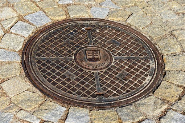 A metal manhole cover on a paved road surface, symmetrical and stable, manhole cover, Skalica, Skalitz, Trnavsky kraj, Slovakia, Europe