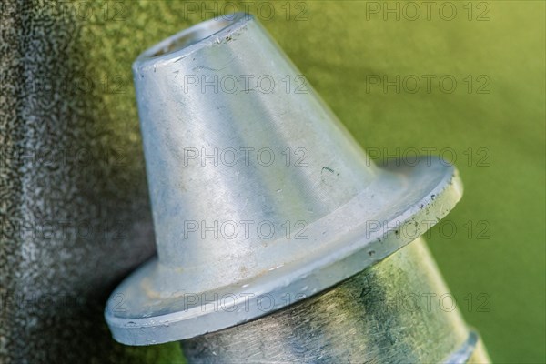 Closeup of triangle shaped flanged metal nozzle of air hose on blurred grayish green background