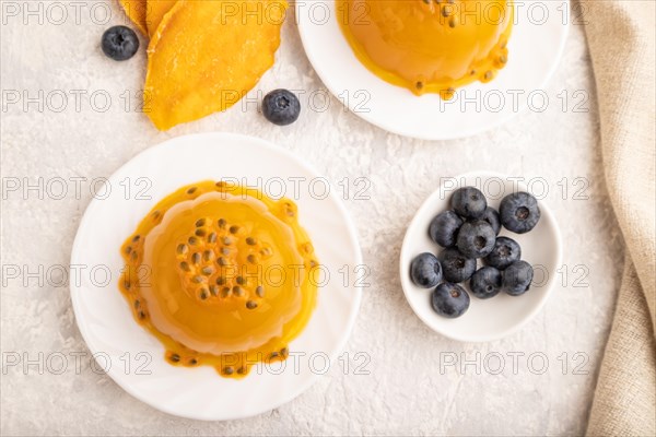 Mango and passion fruit jelly with blueberry on gray concrete background and linen textile. top view, flat lay, close up