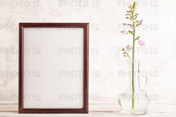 Wooden frame with hosta flowers in glass vase on gray concrete background. side view, copy space, still life, mockup, template, spring, summer concept