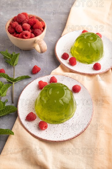 Mint and raspberry green jelly on gray concrete background and orange linen textile. side view, close up