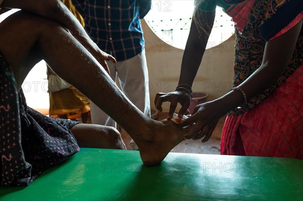 Nurse treating a man with a wound on his right foot, rural health centre, Tamil Nadu, India, Asia
