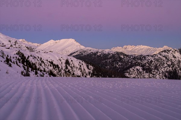 Snow-covered mountains at dusk with a purple sky and a freshly groomed ski slope in the foreground, Belalp, Naters, Brig, Canton Valais, Switzerland, Europe