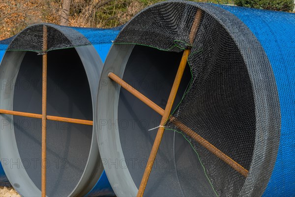 Closeup of large blue sections of steel industrial pipes sitting at construction site