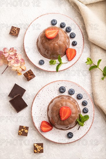 Chocolate jelly with strawberry and blueberry on gray concrete background and linen textile. top view, flat lay, close up