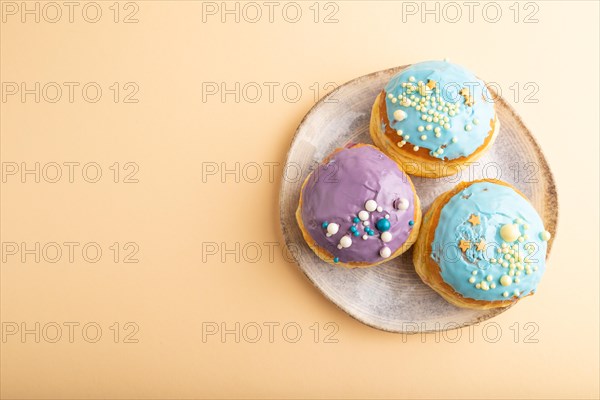 Purple and blue glazed donut on orange pastel background. top view, flat lay, copy space. Breakfast, morning, concept