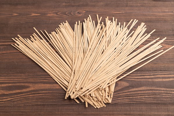 Japanese buckwheat soba noodles on brown wooden background. Side view, close up