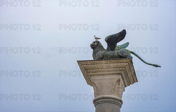 Winged lion of Saint Mark, old bronze statue on a column in San Marco square, famous tourist attraction in Venice. Italy