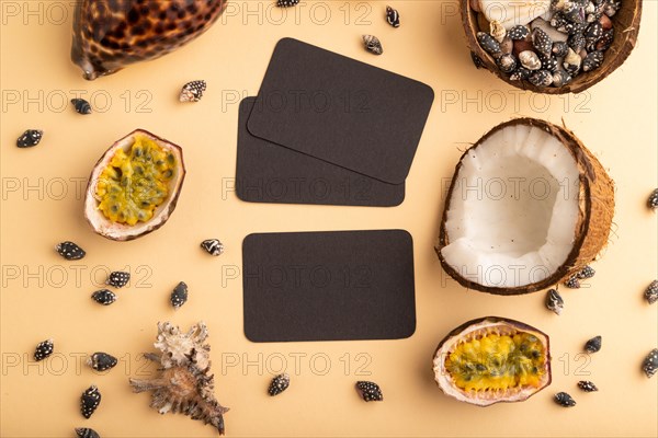 Brown paper business card with coconut, passion fruit, seashells, on orange pastel background. Top view, flat lay, copy space. Tropical, healthy food, vacation, holidays concept