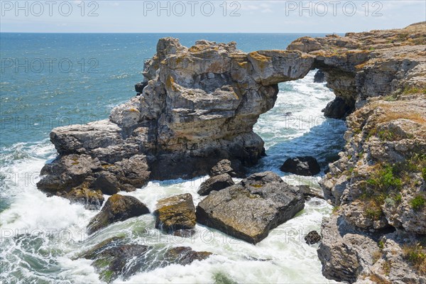 Picturesque rock arch on the coast with foamy waves, summer blue sky and signs of erosion, stone arch, Tyulenovo, Tyulenovo, Shabla, Dobrich, Black Sea, Bulgaria, Europe