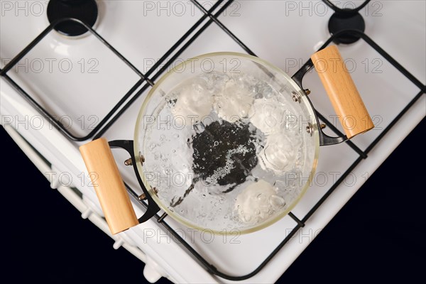 Top view of transparent glass saucepan with boiling eggs on a gas stove