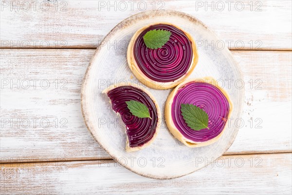 Sweet tartlets with jelly and milk cream on a white wooden background. top view, flat lay, close up