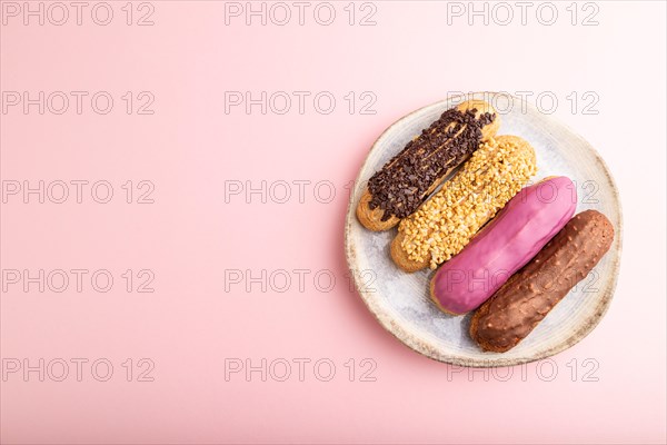 Set of eclair, traditional french dessert on ceramic plate on pink pastel background. top view, flat lay, copy space, still life. Breakfast, morning, concept