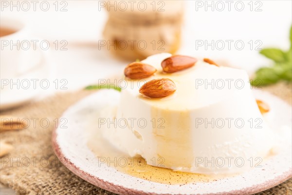 Ricotta cheese with honey and almonds on white wooden background and linen textile. side view, close up, selective focus