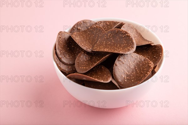 Chocolate chips with caramel on pink pastel background. side view, close up