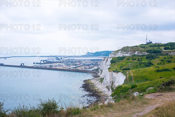 View of the harbour and town of Dover, ship in the bay, next to impressive chalk cliffs under a cloudy sky, White cliffs of Dover, hiking trails, paths along the cliffs overlooking the sea and grassy areas, Doverm South England, England, English Channel, United Kingdom, Europe