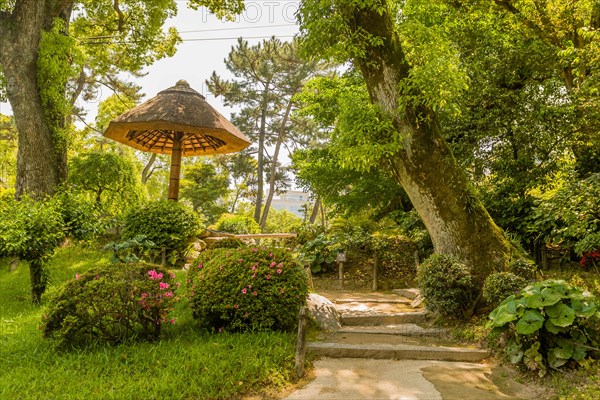 Thatch and bamboo umbrella covered rest area in Japanese garden in Hiroshima, Japan, Asia