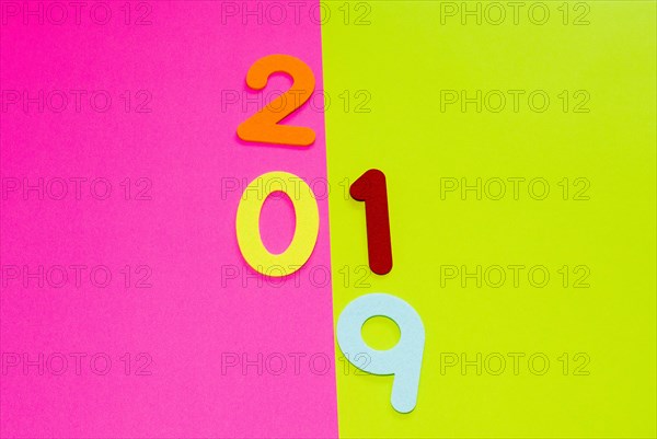 The numbers 2019 made of felt of different colors photographed on pink and yellow background