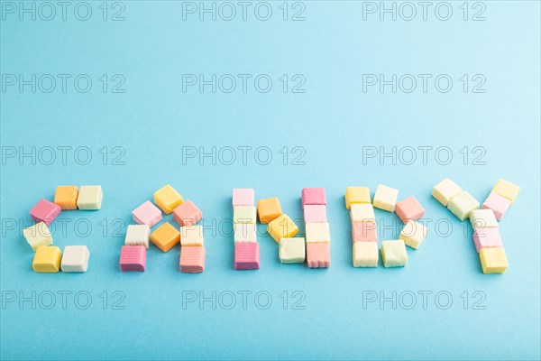 The inscription candy laid out with various fruit jelly chewing candies on blue pastel background. apple, banana, tangerine, side view, copy space