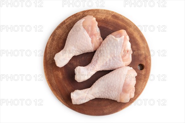 Raw chicken legs on a wooden cutting board isolated on white background. Top view, flat lay, close up