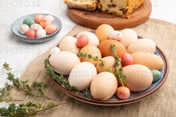 Homemade easter colored eggs on plate and raisins cake on a gray concrete background and linen textile. side view, close up