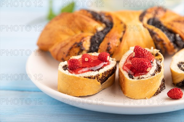 Homemade sweet bun with strawberry jam and cup of green tea on a blue wooden background. side view, close up, selective focus