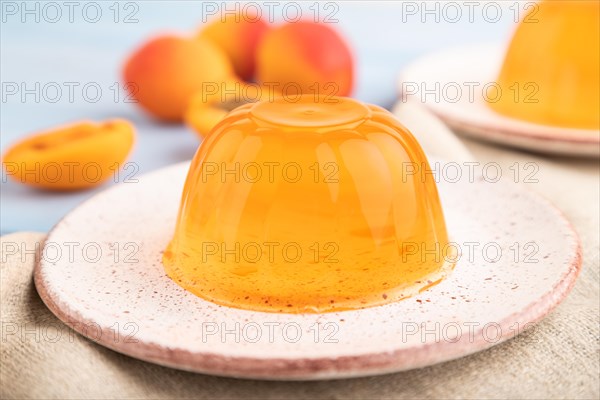 Apricot orange jelly on blue wooden background and linen textile. side view, close up, selective focus