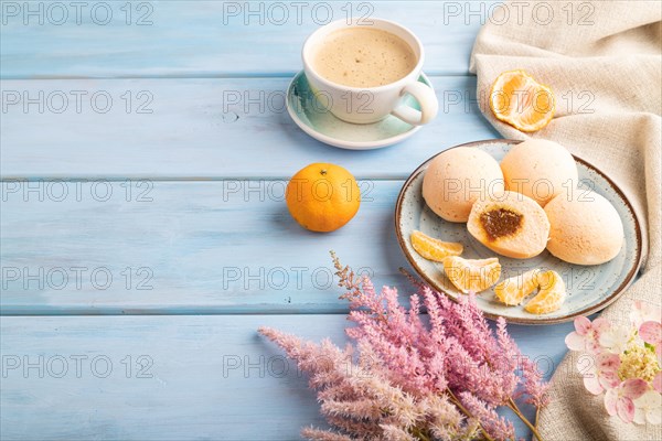 Japanese rice sweet buns mochi filled with tangerine jam and cup of coffee on a blue wooden background and linen textile. side view, copy space
