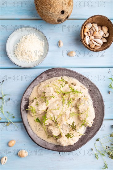 Stewed chicken fillets with coconut milk sauce and mizuna cabbage microgreen on blue wooden background. top view, flat lay, close up