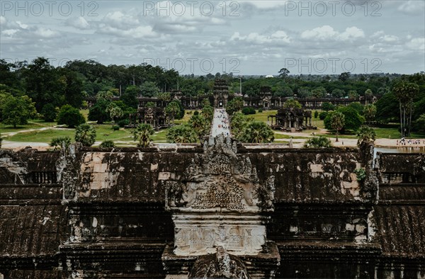 View of the historic Angkor Wat temple complex with lush trees under a cloudy sky. Siem reap, Cambodia, Asia
